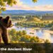 A black bear cub on a bluff looking across a river at earthen mounds.